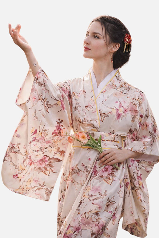 Femme en kimono satin aux motifs floraux, levant une main délicatement tout en tenant des fleurs
