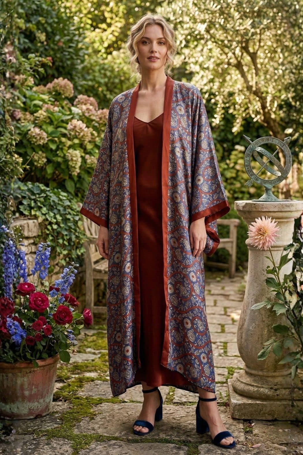 Femme portant un kimono en satin aux motifs floraux, robe marron, dans un jardin verdoyant avec des fleurs colorées
