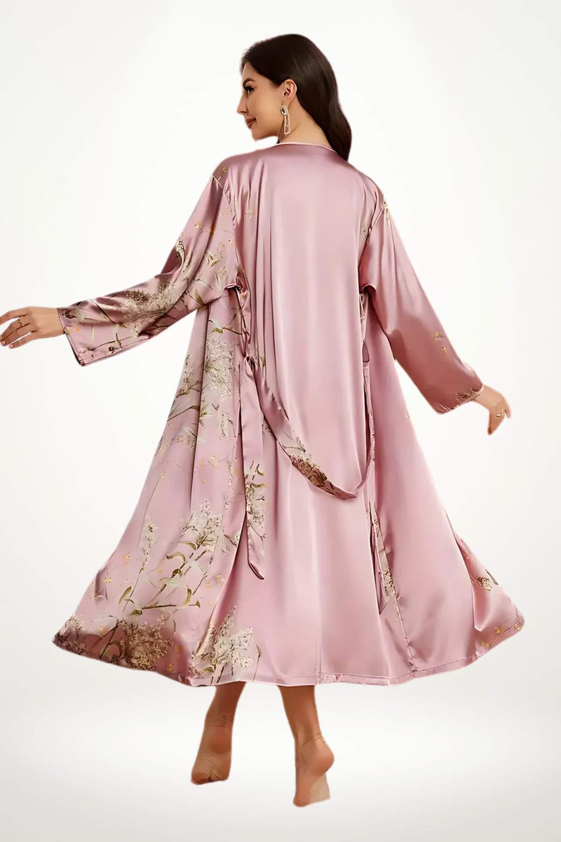 Kimono en satin rose avec des motifs floraux, manches longues, porté avec élégance dans un décor minimaliste
