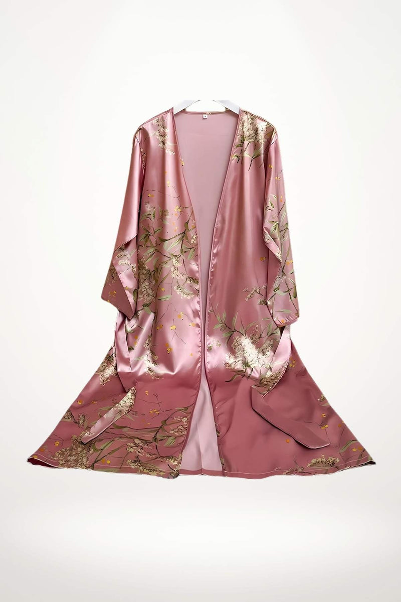 Kimono en satin rose avec motifs floraux délicats et manches larges, suspendu sur un cintre
