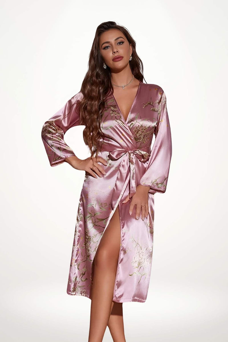 Kimono en satin rose avec motifs floraux, décolleté en V et fente, porté par une femme aux cheveux ondulés