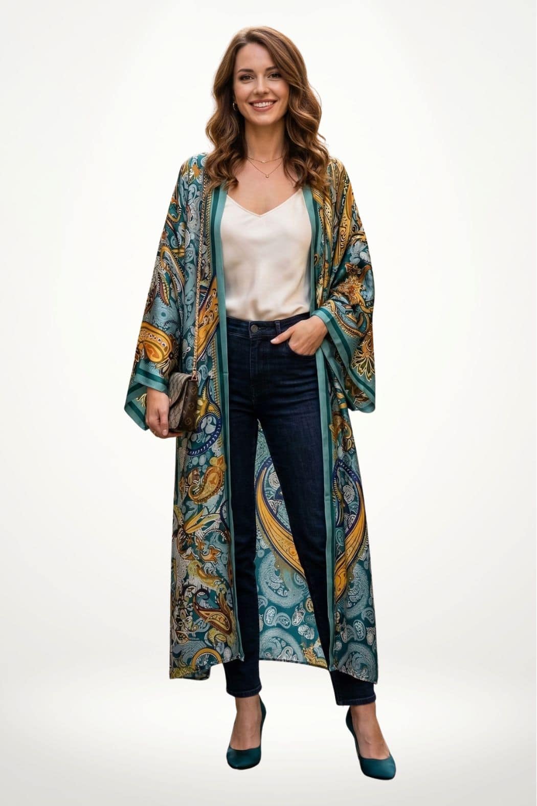 Femme souriante portant un long kimono en satin aux motifs colorés, avec un fond neutre et des jeans foncés