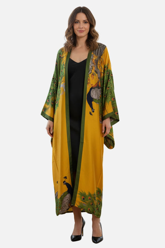 Femme portant un long kimono en satin jaune et vert avec motifs de paons, sur fond blanc