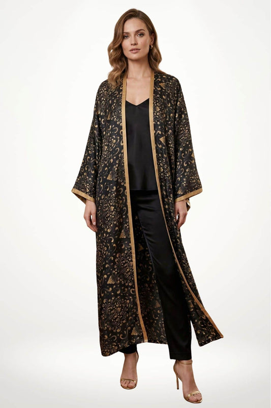 Femme portant un long kimono en satin noir avec des motifs dorés, décoré d'une bordure dorée, sur fond blanc