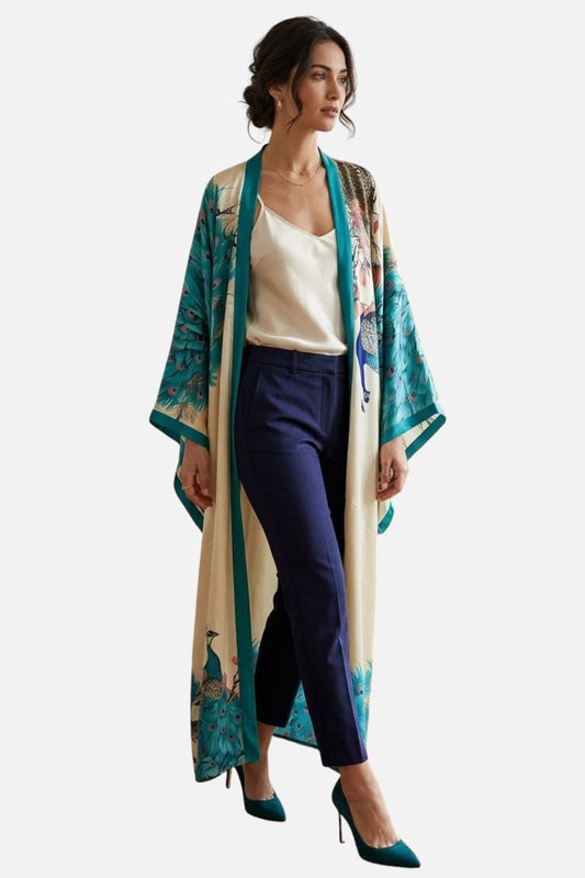 Femme portant un long kimono aux motifs de paon, associé à un top blanc et un pantalon bleu marine