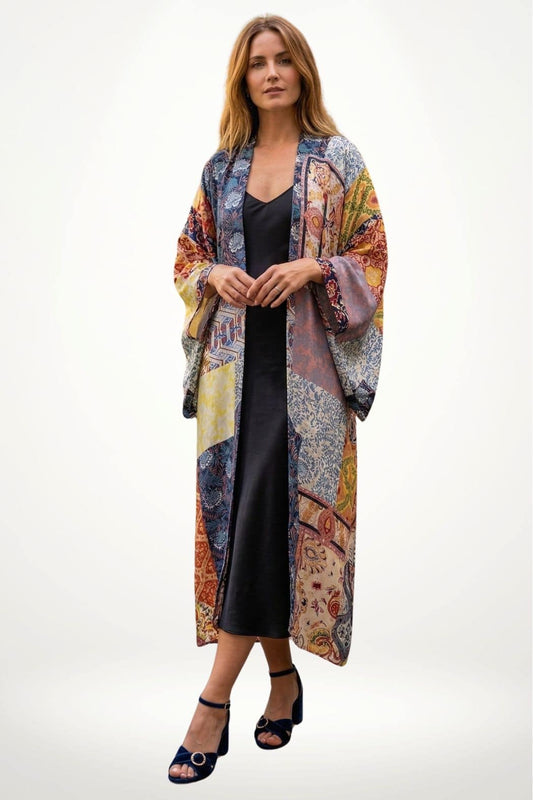 Femme portant un long kimono coloré aux motifs variés, avec une robe noire et des sandales à talons