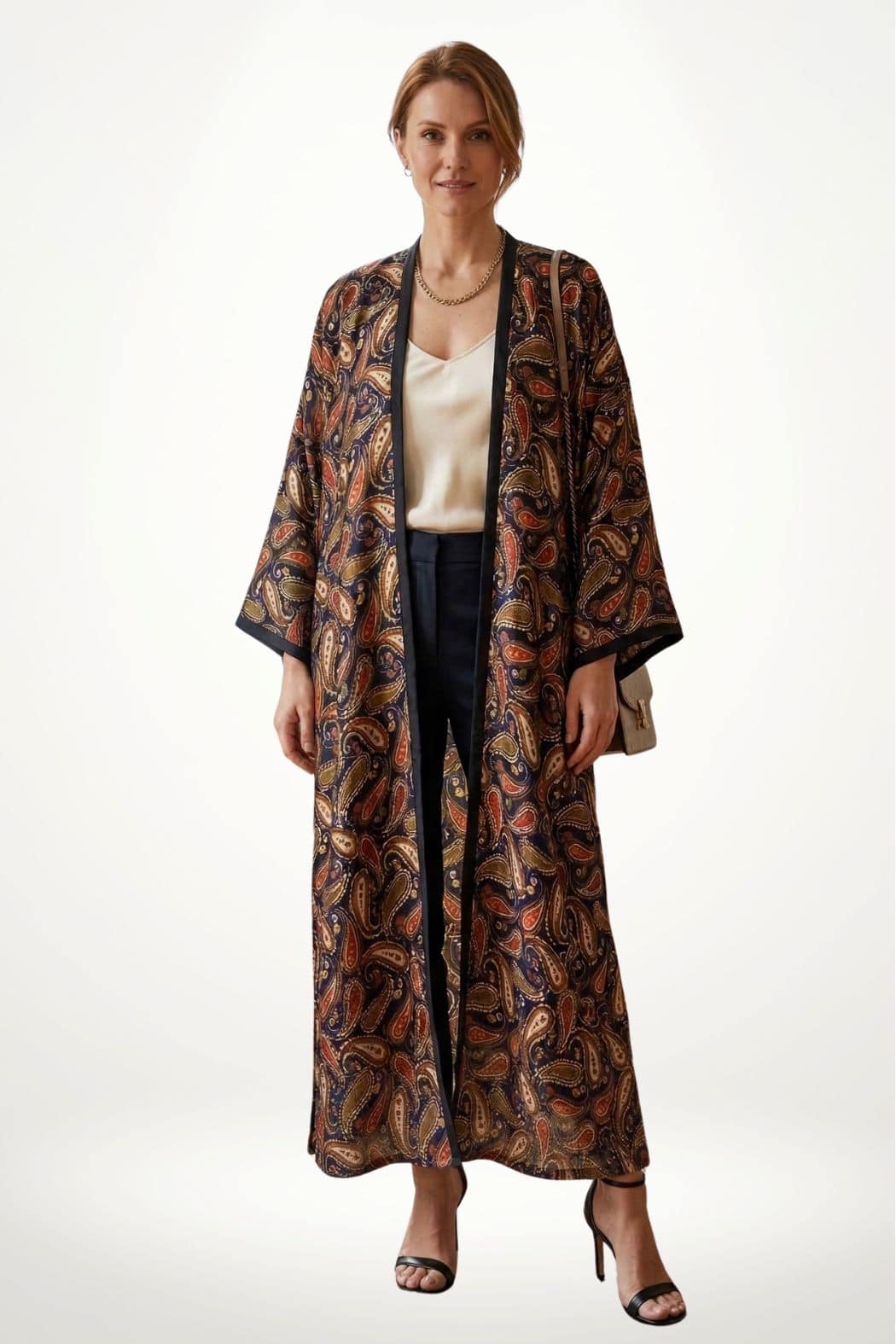 Femme portant un kimono en satin aux motifs paisley colorés, avec un fond clair et une posture élégante
