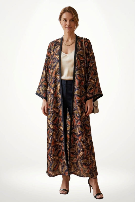 Femme portant un kimono en satin aux motifs paisley colorés, avec un fond clair et une posture élégante