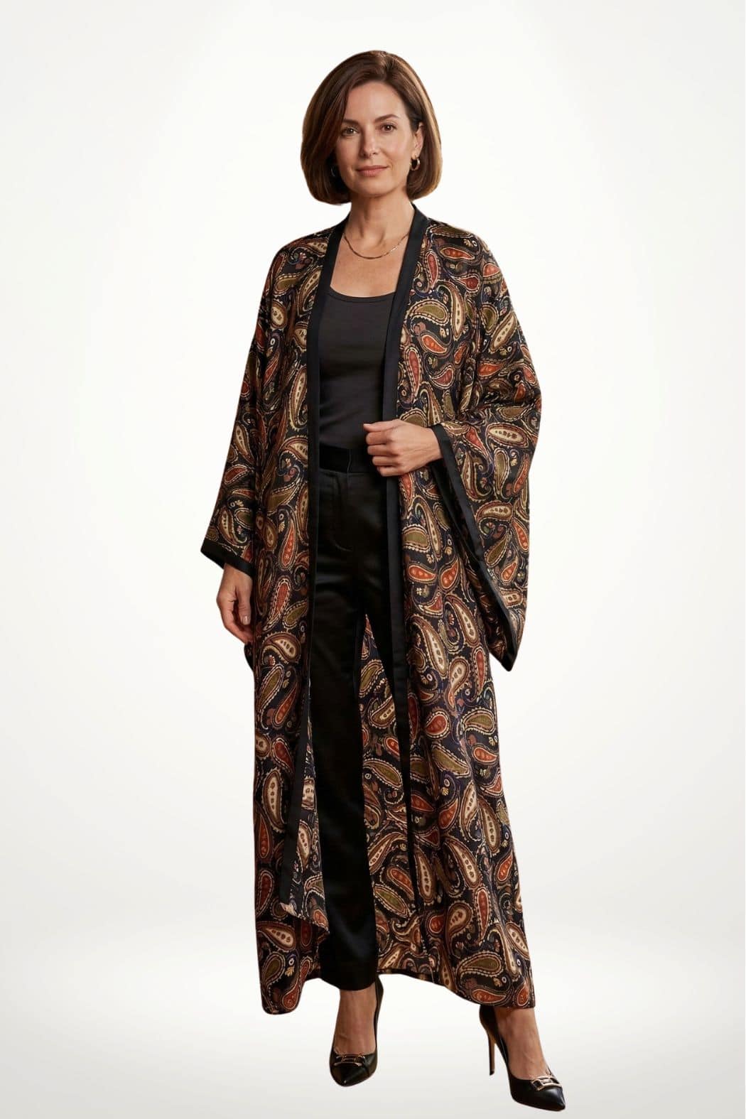Femme portant un kimono long en satin aux motifs paisley colorés, avec un pantalon noir et des escarpins