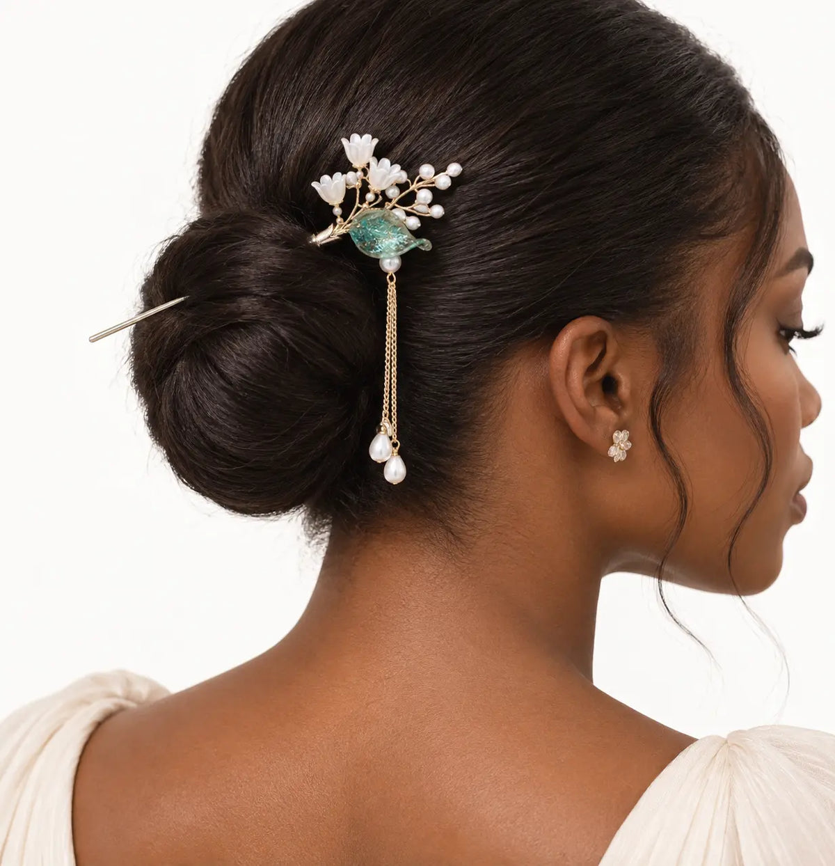 Chignon orné d’un bijou floral blanc aux détails verts.