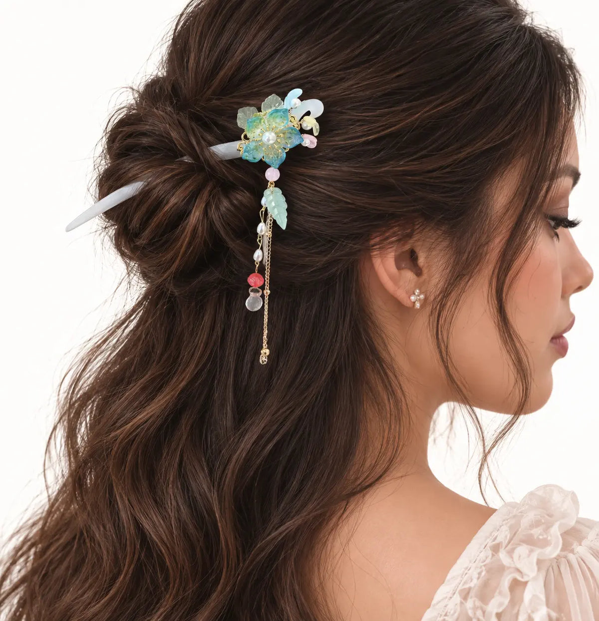 Chignon décoré d’un bijou à fleur irisée et perles pastel.