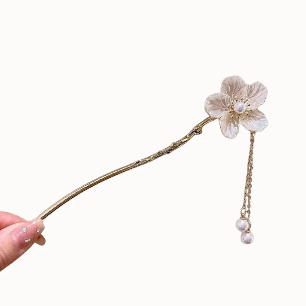 Ornement doré à fleur ivoire avec chaînette et perle pendante.