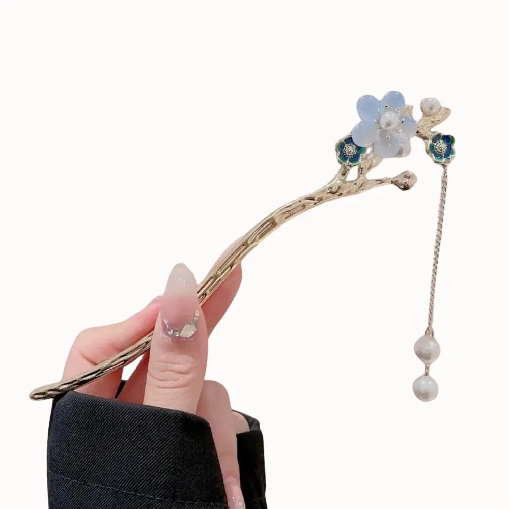 Bijou de cheveux avec fleurs bleues sur branche dorée.