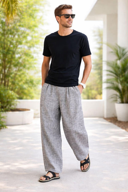 Homme portant un t-shirt noir et un pantalon hakama gris, marchant sur un chemin ensoleillé entouré de verdure