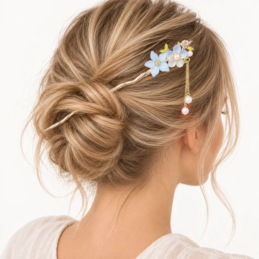 Chignon blond orné d’un peigne à petites fleurs bleues et perles.