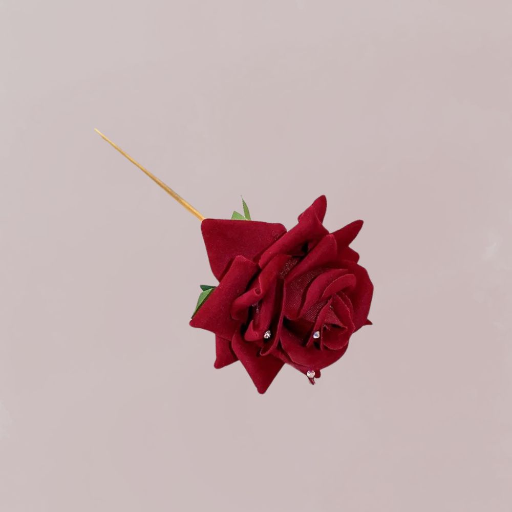Épingle à cheveux en velours rouge représentant une rose, ornée de petites perles, sur fond rose pâle