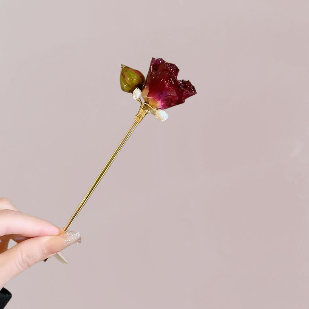 Peigne à cheveux en or avec une rose séchée rouge et un bouton vert, sur fond rose