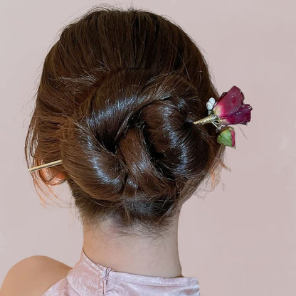 Coiffure en chignon avec peigne doré et fleur rose séchée sur fond rose