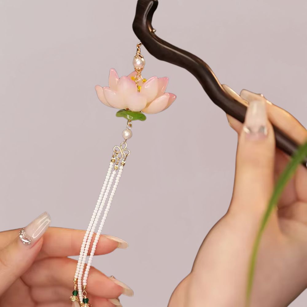 Peigne en bois noir avec une fleur de lotus rose et des perles blanches suspendues, sur fond neutre