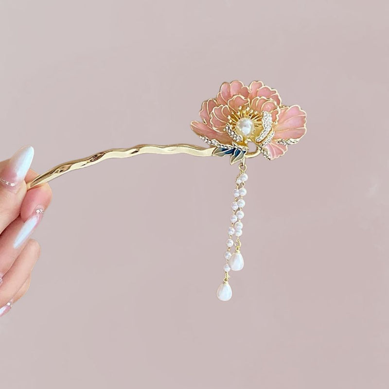Accessoire cheveux en métal doré avec une fleur rose et des perles blanches suspendues, sur fond neutre