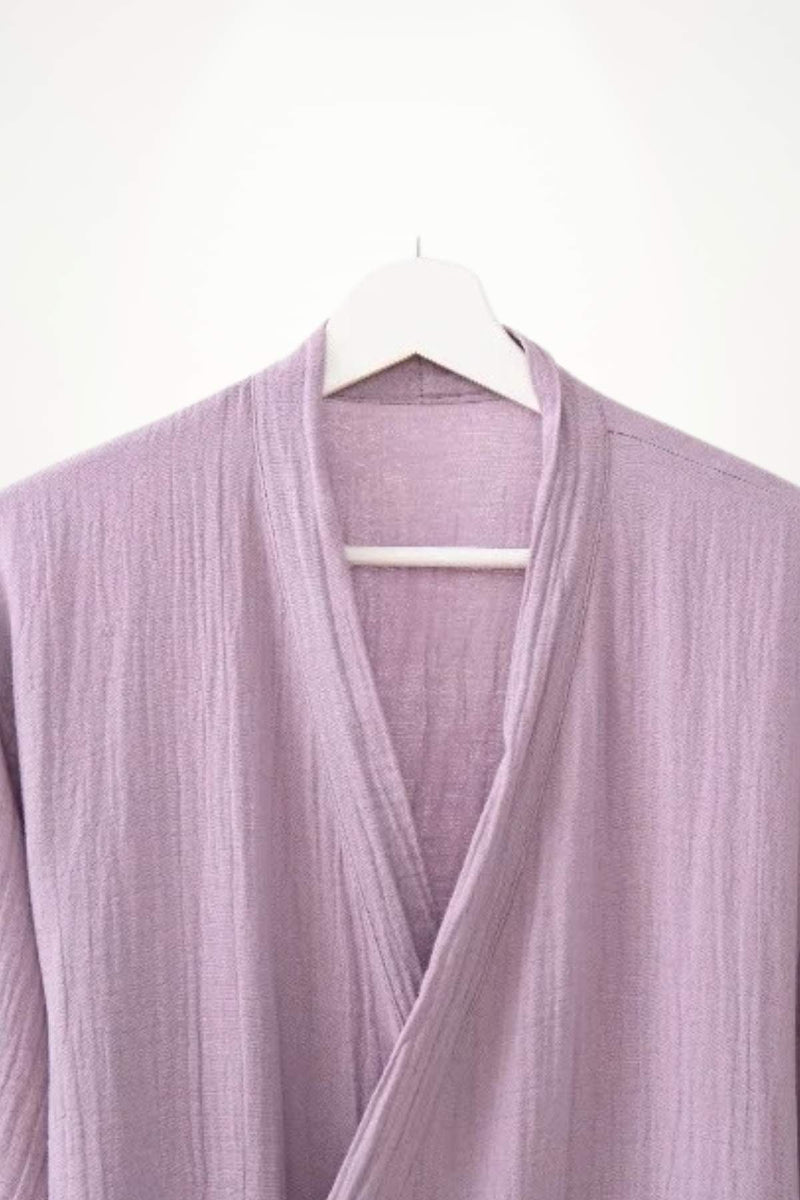 Peignoir kimono en coton de couleur lilas, avec une texture douce et des plis délicats, suspendu sur un cintre