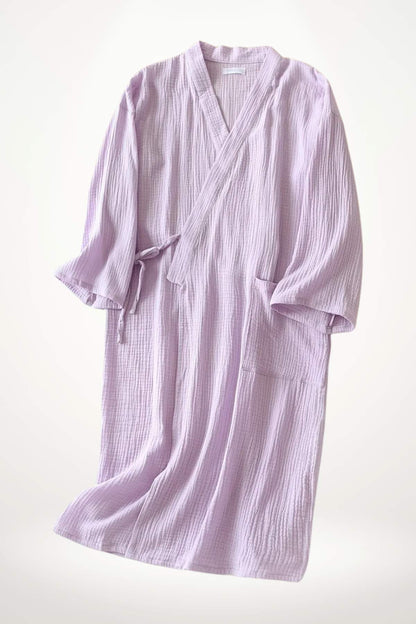 Peignoir kimono en coton de couleur lilas, avec une texture douce et des manches larges, suspendu sur fond clair
