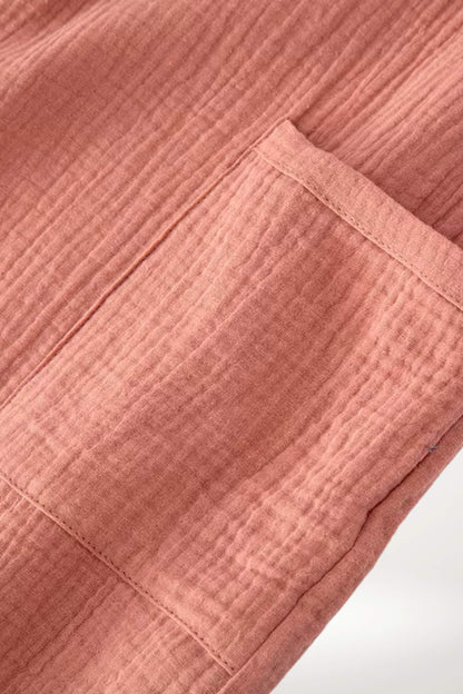 Tissu en coton rose doux avec un motif texturé, présentant une poche sur le côté du peignoir kimono