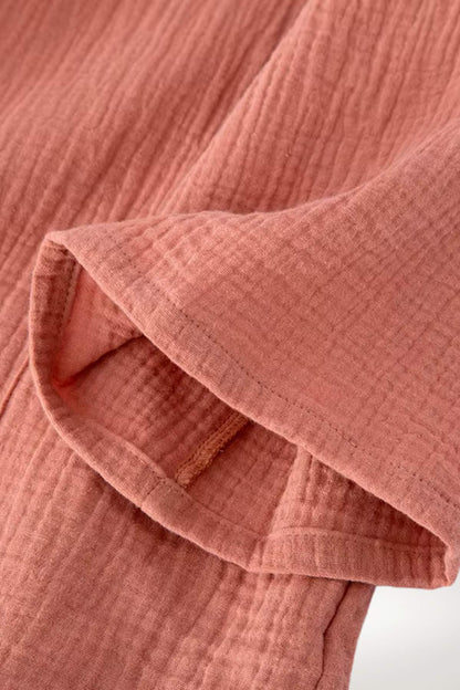 Un peignoir kimono en tissu doux de couleur rose, avec des manches courtes et un motif texturé délicat