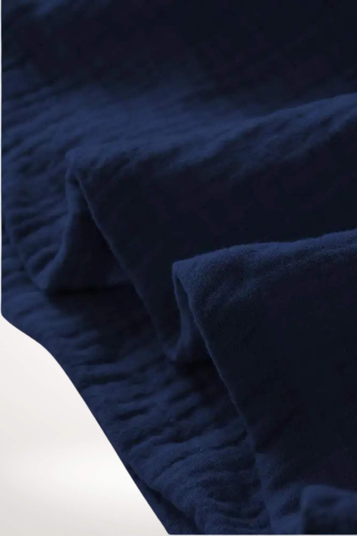 Tissu en coton bleu nuit, doux et texturé, plié avec soin, évoquant un style japonais apaisant