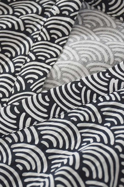 Détails d'un peignoir en coton avec un motif ondulé noir et blanc, mettant en avant des textures douces et élégantes