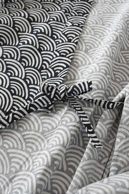 Peignoir kimono en coton avec motifs ondulés noirs et blancs, noué sur le côté, sur fond gris clair