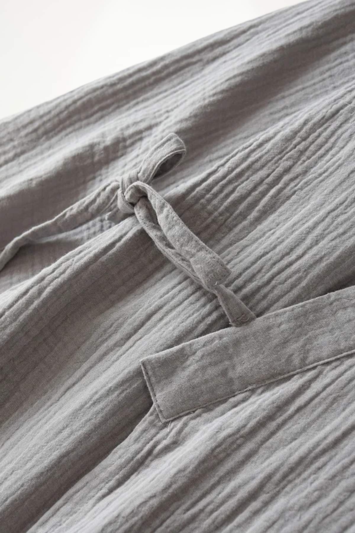 Peignoir kimono en tissu léger gris, avec une texture plissée et une ceinture nouée sur le devant