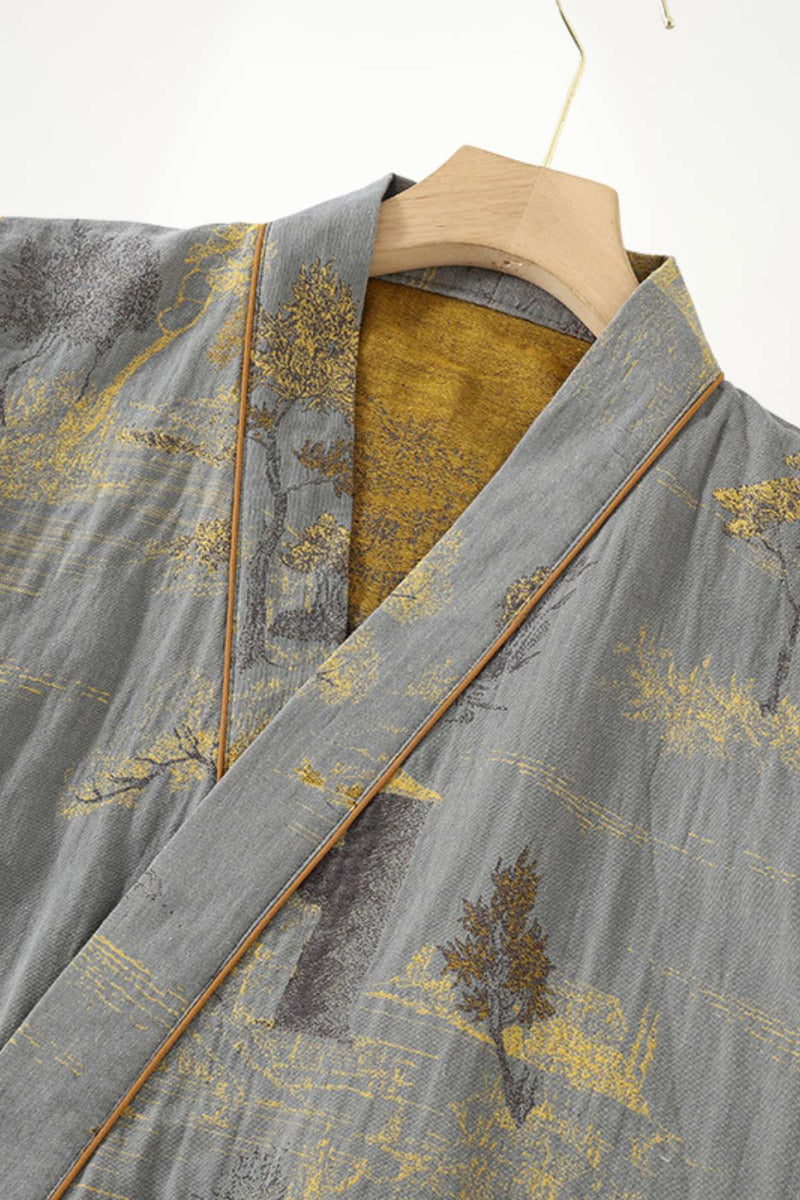 Kimono en tissu gris avec motifs dorés et arbres, col en contraste jaune, suspendu sur un cintre en bois