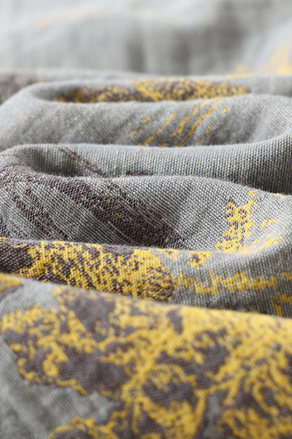 Tissu en lin gris avec motifs floraux jaunes et bruns, drapé de manière fluide et élégante
