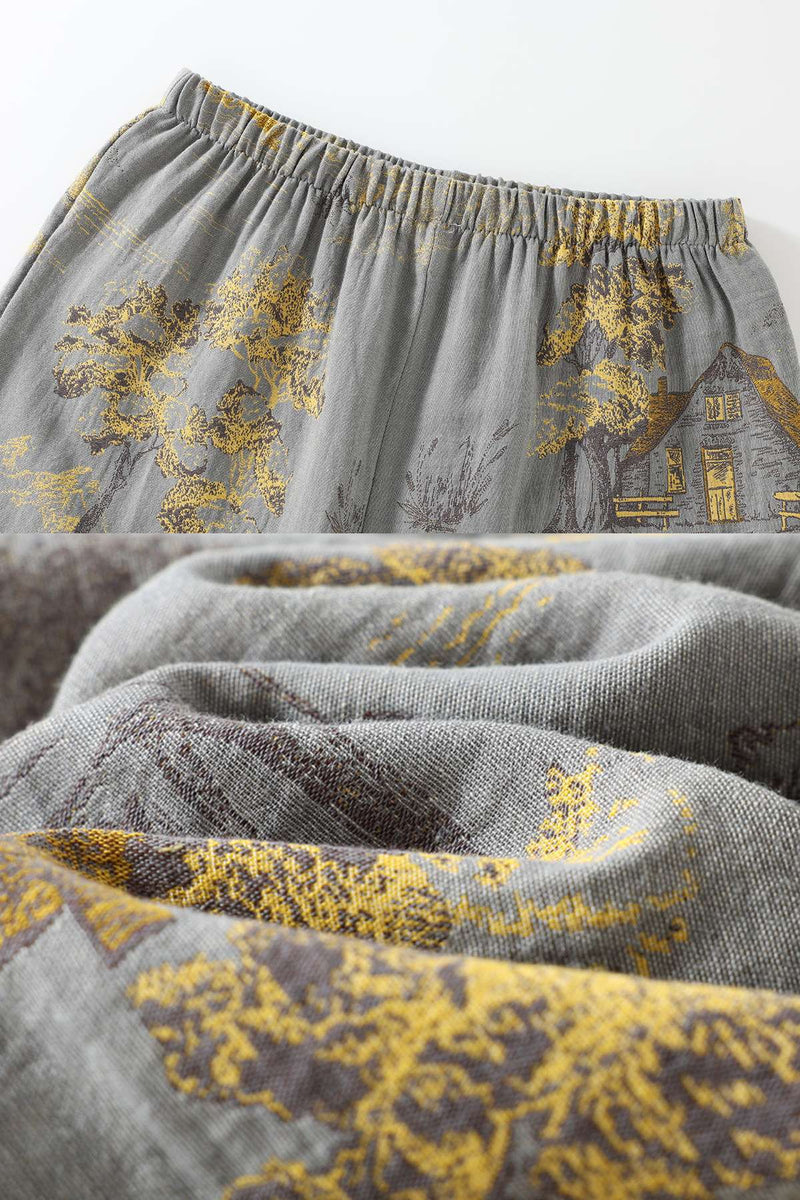 Tissu gris avec motifs dorés représentant des arbres et une maison, offrant une texture douce et confortable