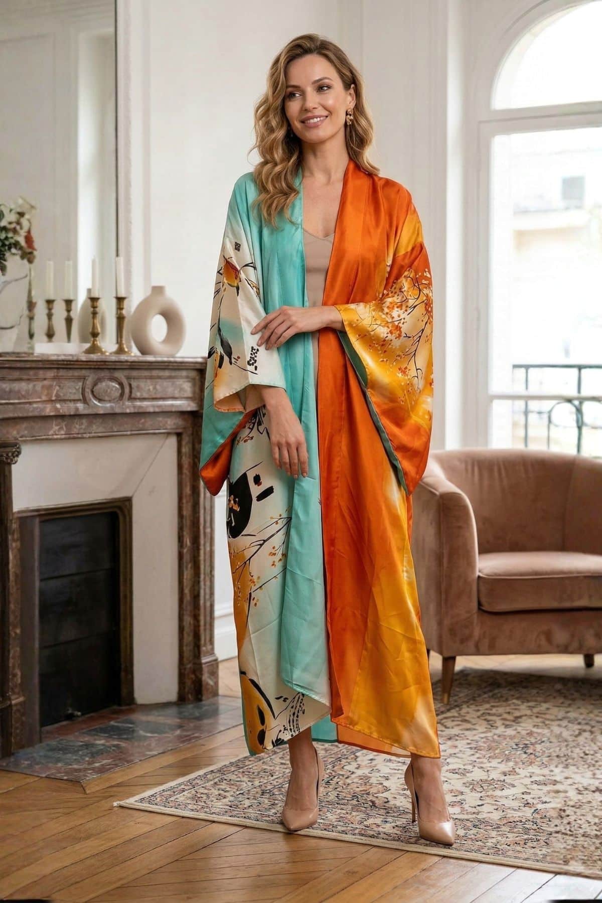 Femme souriante portant un kimono long aux couleurs turquoise et orange, dans un décor élégant avec un canapé et des