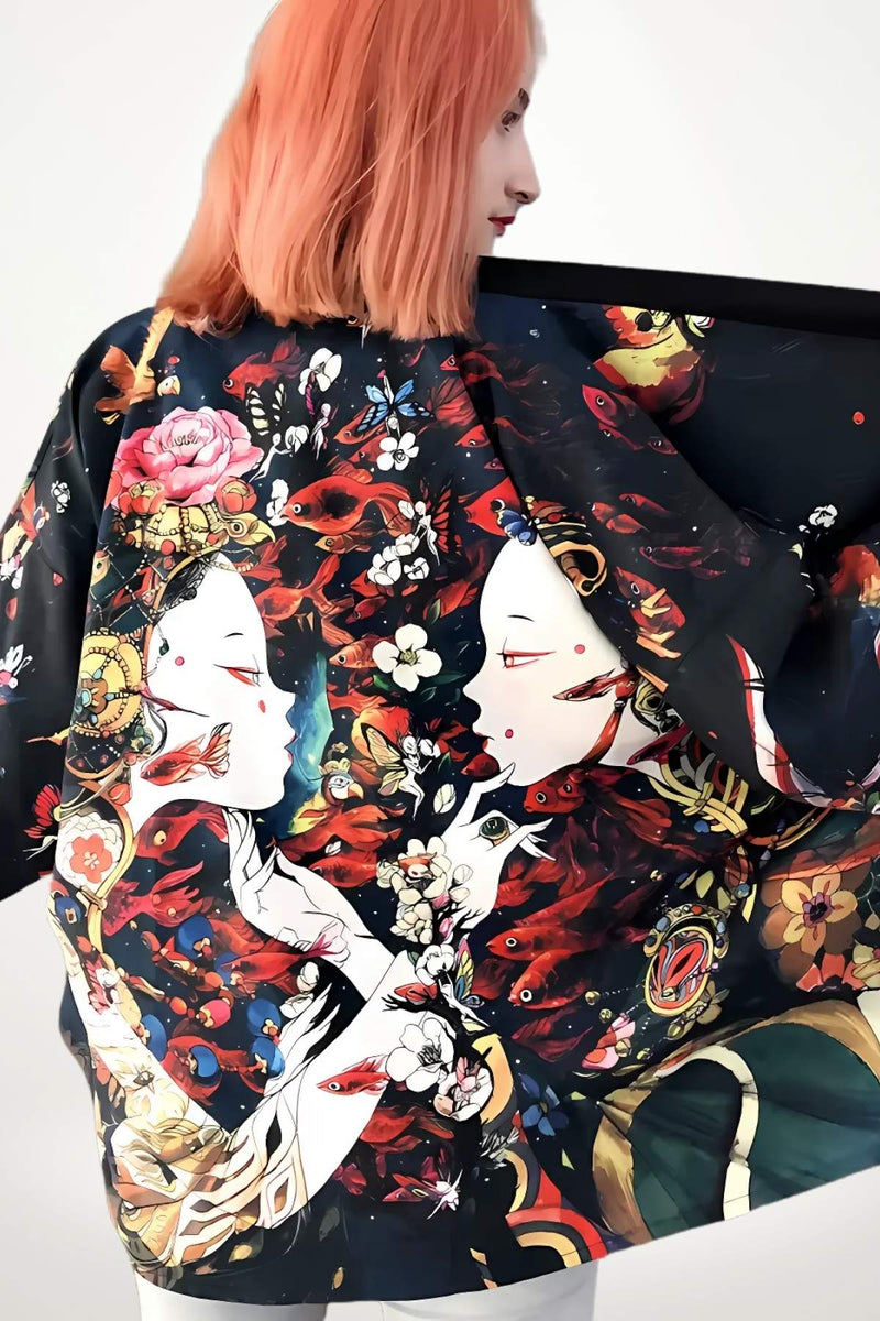 Veste kimono femme en tissu noir, ornée de motifs floraux et de visages stylisés, portée avec une posture décontractée