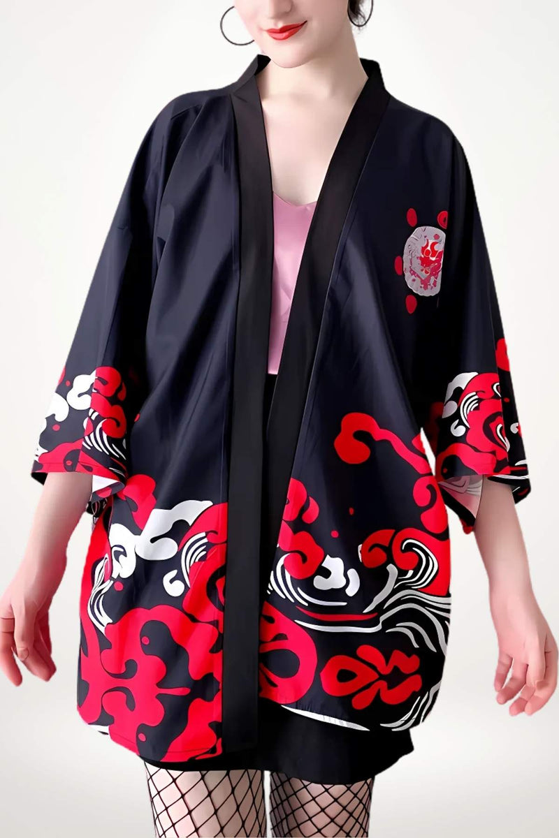Veste kimono femme noire avec motifs rouges et blancs, portée sur un haut rose, dans un décor minimaliste