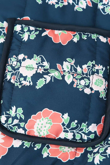 Gros plan sur l'imprimé floral corail et vert de la veste kimono matelassée de la poche
