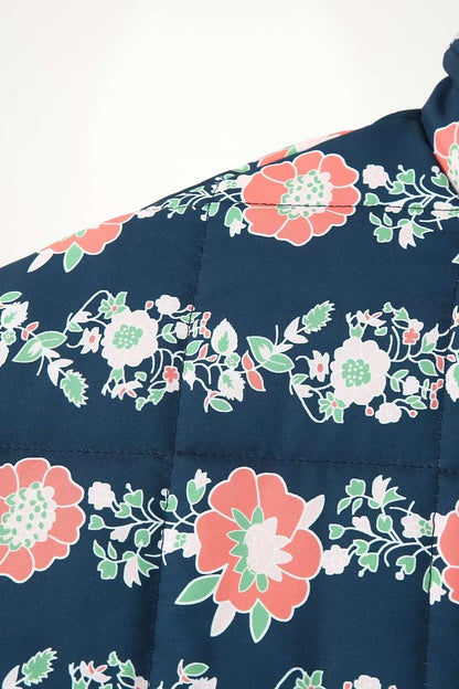 Gros plan sur l'imprimé floral corail et vert de la veste kimono matelassée sur le haut de la veste