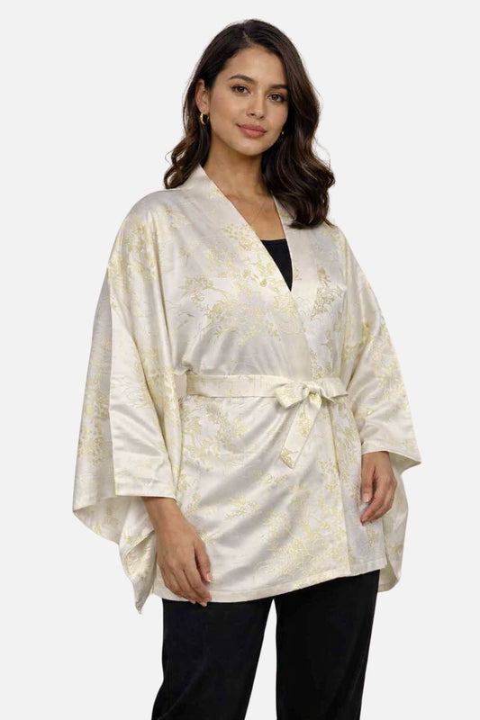 Femme portant un yukata beige avec des motifs dorés, dans une lumière blanche douce, avec un décor minimaliste